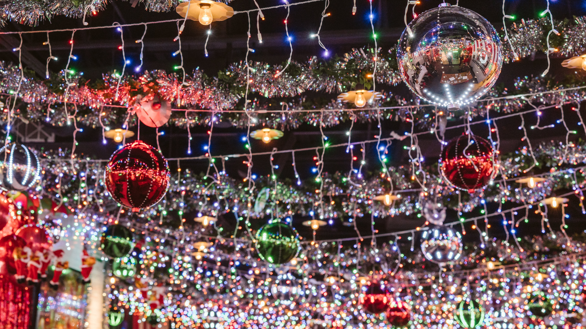 Ceiling decorated for the holidays with lights, tinsel garland, and red, green, and silver ornaments.